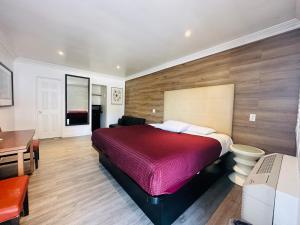 1 dormitorio con cama roja y escritorio en Casa Blanca Inn & Suites Whittier en Whittier