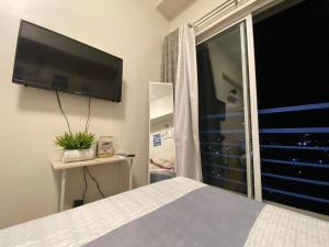 a bedroom with a bed and a flat screen tv at Studio unit at The Loop in Cagayan de Oro