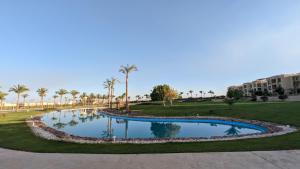 una piscina en un parque con palmeras y edificios en Golf Heights Sea and Mountain View Studio with Free Wi-Fi en Sharm El Sheikh