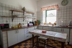 eine Küche mit einem Tisch, einem Waschbecken und einem Fenster in der Unterkunft Piros Ponty Panzió in Poroszló