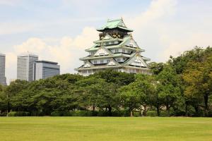 ein großer Turm in einem Park mit Bäumen und Gebäuden in der Unterkunft オリエントシティ南堀江Ⅱ in Osaka