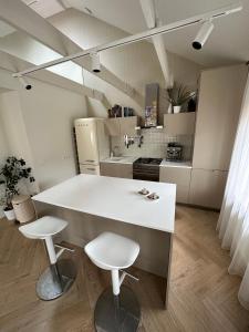 a kitchen with a white counter and two stools at The Most Central Apartment in Kaunas