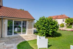 a house with a yard with two white chairs at L'Escale de Jules et Lily in Bligny-lès-Beaune