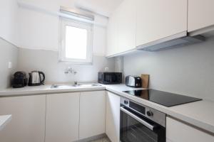 a kitchen with white cabinets and a sink and a window at Impressive Minimal 2 bdrm next to Acropolis Museum in Athens