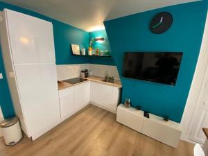 uma cozinha com armários brancos e uma parede azul em Le Cocon de Jeanne em Rouen