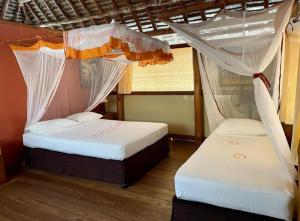 two beds with mosquito nets in a room at Barry's Beach Resort in Mkwaja