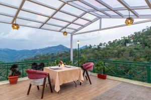 una mesa y sillas en un balcón con vistas en Maple Resort Chail, en Shimla