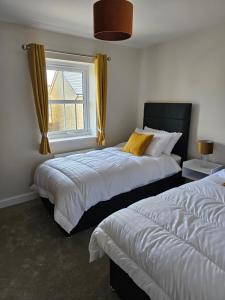 ein Schlafzimmer mit zwei Betten und einem Fenster in der Unterkunft The Neal's 4 Bedroom House in Buxton Sleeps 8 in Buxton