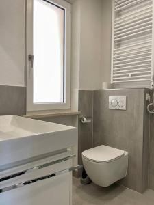 ein Badezimmer mit einem weißen WC und einem Waschbecken in der Unterkunft NEU Suite Perlago, Whirlpool & Seeblick in Tignale