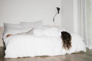 Eine Frau, die auf einem Bett unter einer weißen Decke liegt. in der Unterkunft Riders Hotel in Laax