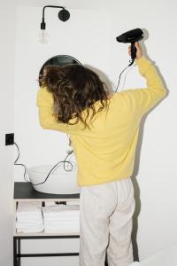 a person holding a hair dryer in a room at Riders Hotel in Laax