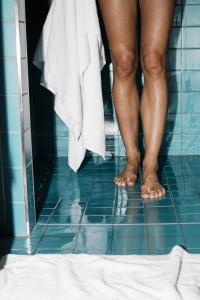 Ein paar Beine stehen in einem Badezimmer in der Unterkunft Riders Hotel in Laax