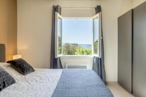 a bedroom with a bed and a large window at Domitia Roussillon Appartement Luberon in Roussillon
