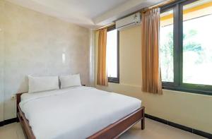 een wit bed in een kamer met 2 ramen bij TwoSpaces Living at D'Rainbow Homestay in Mergoredjo