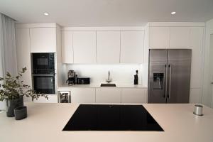 a kitchen with white cabinets and a stainless steel refrigerator at Mara's Apartments Higueron West - Like A House - 246 Square Meters of Private Terrace & Garden - Morning and Evening Sun in Fuengirola