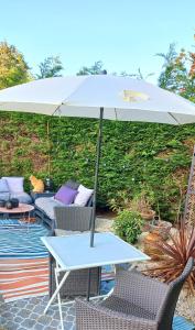 - une table avec un parasol sur la terrasse dans l'établissement Gîte L'Escalier des Rêves - Rouen, à Le Mesnil-Esnard