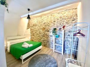 タオルミーナにあるCasa Vacanze Controventoの緑のベッドと石の壁が備わるベッドルーム1室