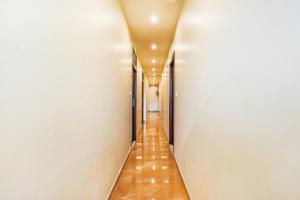 a long corridor with white walls and brown floors at FabHotel Liwa International in Mumbai
