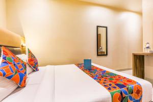 a bedroom with a white bed with a colorful blanket at FabHotel Liwa International in Mumbai