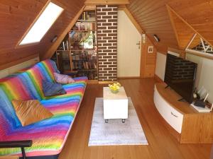 a living room with a rainbow couch and a tv at Wooden cabin with a view in Idrija