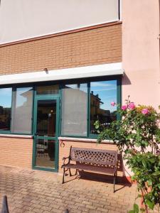 um banco em frente a um edifício com janelas em Villetta Gina a San Giuseppe - Lido di Pomposa em San Giuseppe