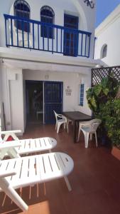 a patio with white chairs and a table and a building at Bungalow in the sun of Maspalomas with large pool in Maspalomas