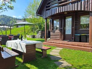 una casa con mesa, banco y sombrilla en Wooden cabin with a view, en Idrija