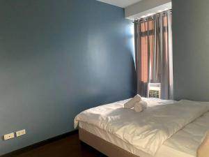 een slaapkamer met een bed met een blauwe muur bij Gramercy Residences Sunset View Condo 1 Bedroom Flat in Manilla