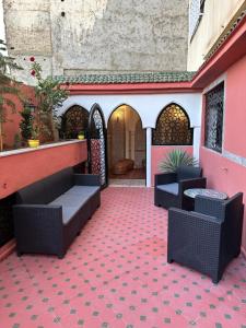 um pátio com cadeiras e mesas num piso vermelho em APPARTEMENTS NIA CONFORT, Plein centre ville, avec TERRASSE em Fez