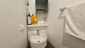 a white bathroom with a sink and a towel at Guesthouse The Kims in Seoul