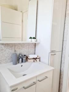 W białej łazience znajduje się umywalka i lustro. w obiekcie Apartment in Murter w mieście Murter