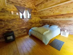 1 dormitorio con 1 cama en una cabaña de madera en Chez Tombivouac, en Pierrefonds