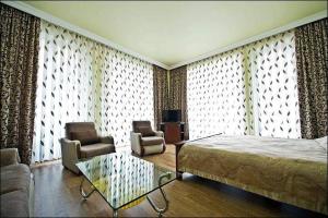 a bedroom with a bed and a couch and chairs at Eiffel Hotel in Batumi