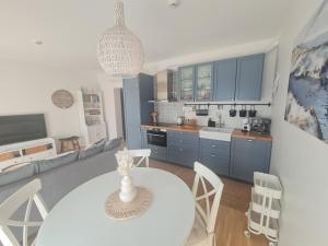 a kitchen and living room with a white table and chairs at Smeltė - Holiday Apartment in Juodkrantė in Juodkrantė