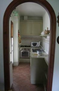 a kitchen with an archway into a kitchen with a stove at Villino Oliva in Pomonte