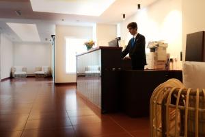 Hotel Vértice Chipiona Mar في تشايبيونا: رجل في بدلة واقف عند كاونتر
