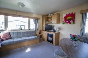 - un salon avec un canapé et une table dans l'établissement Lovely Caravan With Decking At Manor Park Nearby Hunstanton Beach Ref 23017t, à Hunstanton
