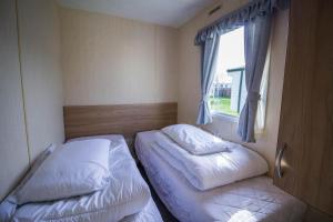 um pequeno quarto com 2 camas e uma janela em Lovely Caravan With Decking At Manor Park Nearby Hunstanton Beach Ref 23017t em Hunstanton