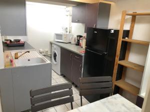 a kitchen with a black refrigerator and a sink at à pied dans l eau écolo 97434 in L'Ermitage-Les-Bains