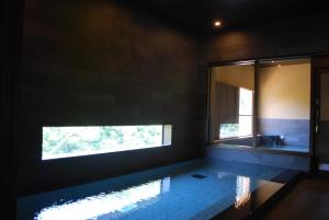 łazienka z lustrem, umywalką i oknem w obiekcie Hakone Suimeisou w mieście Hakone