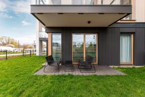 a group of chairs sitting on a deck in front of a house at Apartment Porto near the sea in Gdansk in Gdańsk