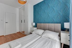 a bedroom with a bed and a blue wall at Apartment Porto near the sea in Gdansk in Gdańsk