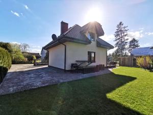 uma pequena casa branca com um jardim de relva em Domek wypoczynkowy Zielonka z JACUZZI em Szczytno