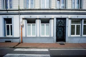 Gîte La Petite Ourse في Andenne: مبنى فيه باب اسود ونوافذ على شارع