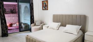 a bedroom with a bed and a chair and a window at APPARTEMENTS NIA CONFORT, Plein centre ville, avec TERRASSE in Fez