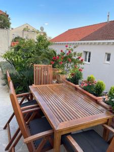 a wooden table and chairs on a patio with flowers at Apartments Tomas in Dubrovnik