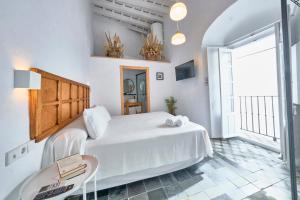 a white bedroom with a large bed and a table at Bekkeh in Vejer de la Frontera