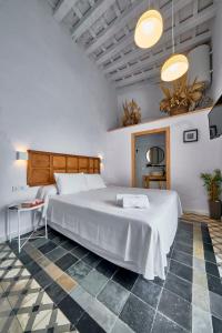 um quarto com uma grande cama branca e um piso em xadrez em Bekkeh em Vejer de la Frontera