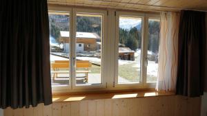 ein Fenster in einem Zimmer mit Blick auf ein Haus in der Unterkunft Ufem Egg Ferienwohnungen in Innertkirchen