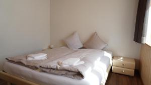 uma cama com lençóis brancos e almofadas em Ufem Egg Ferienwohnungen em Innertkirchen